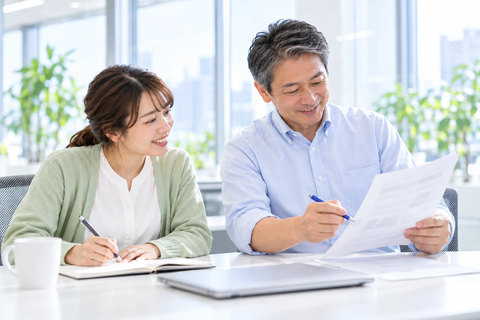 印刷したレビュー結果にペンで印を付ける営業部長と、隣でノートに書き留める営業担当