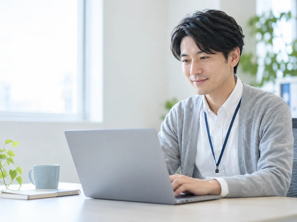 朝のオフィスで、ノートパソコンでQ&Aを確認するサポート担当者