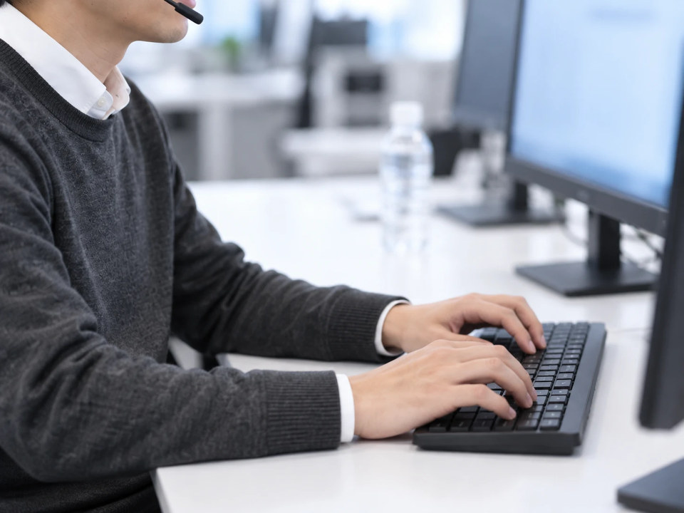 ヘッドセットで話しながら、キーボードでキーワードを入力するオペレーターの手元